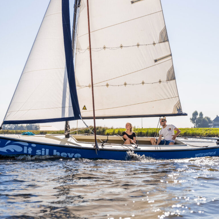 Een jongeman en een jonge dame in een polyvalk van polyvalk verhuur de Wetterspetter die wordt verhuurt, zeilt over het Heegermeer in Friesland