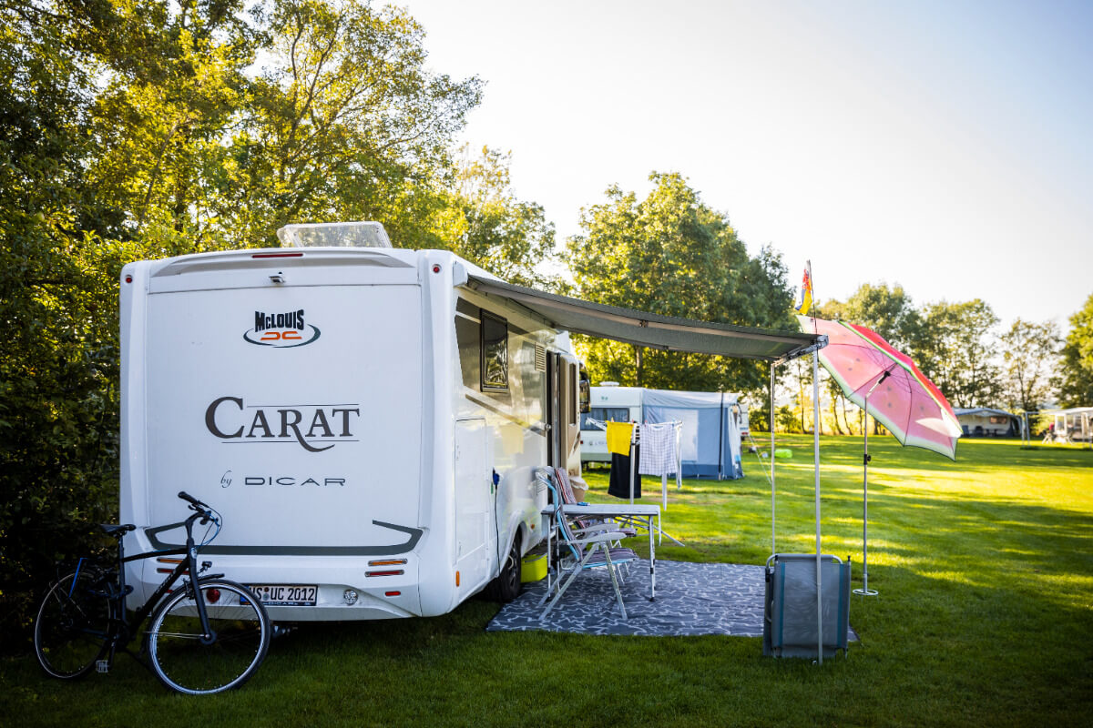 Een verharde camperplaats waar je uitstap op een mooi grasveld omringt door bomen op minicamping de Wetterspetter