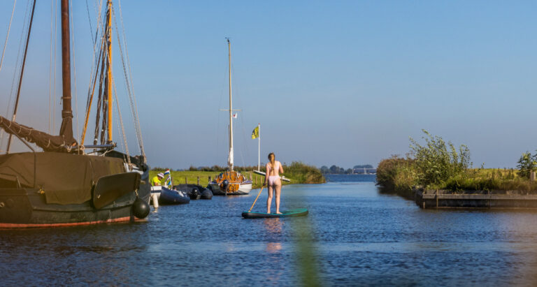 Jonge dame aan het suppen met een gehuurd sup plank bij de haven van minicamping de Wetterspetter aan het Heegermeer