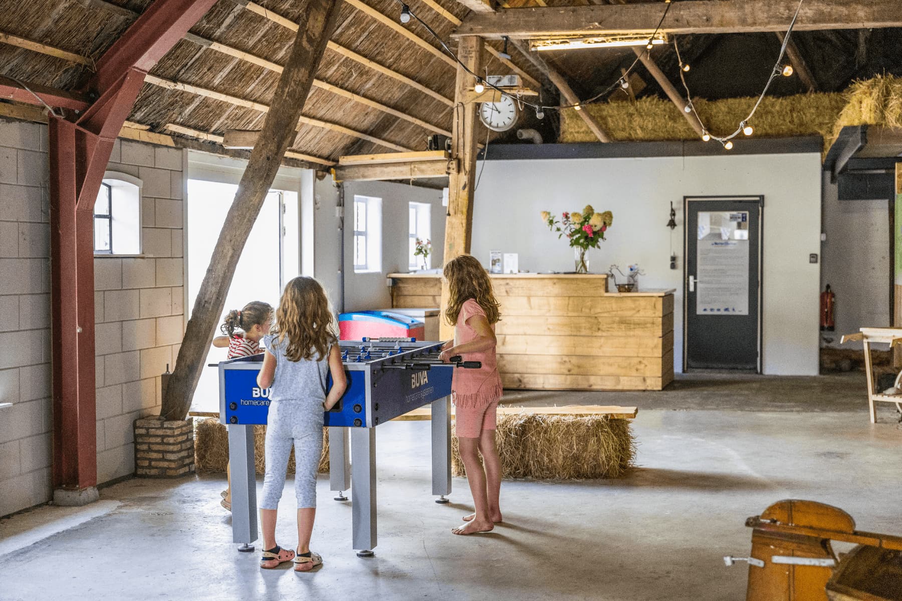 In schuur zijn 3 kinderen aan het spelen met een tafelvoetbaltafel op de Wetterspetter