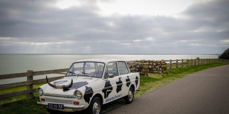 In een oude DAF met koeienvlekken erop langs de IJsselmeer kust van Friesland touren vanaf minicamping de Wetterspetter met Solex verhuur Friesland